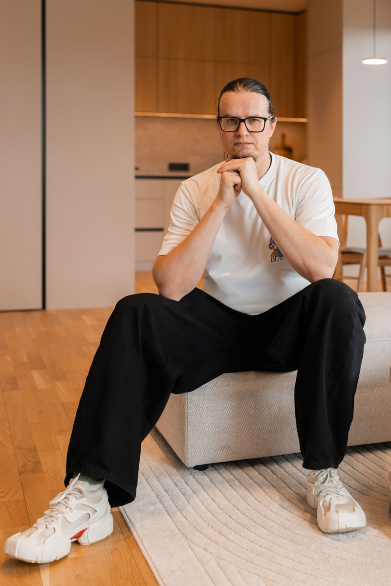 Алексей, дизайнер IDP Studio, в готовой квартире в светлых тонах с деревянной кухней и дубовым паркетом